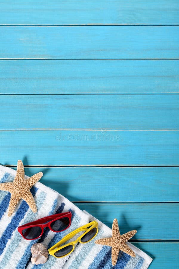Beira do fundo da praia do verão, óculos de sol, toalha, estrela do mar, espaço de madeira azul da cópia, vertical