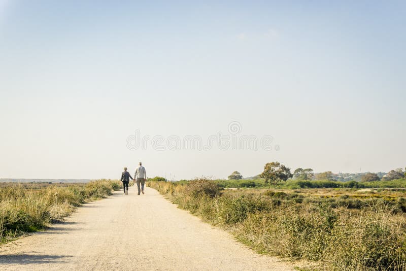 Bejaard paar die in liefde op een stofweg lopen, Portugal stock fotografie Bejaard paar die in liefde op een stofweg lopen, Portugal stock fotografie