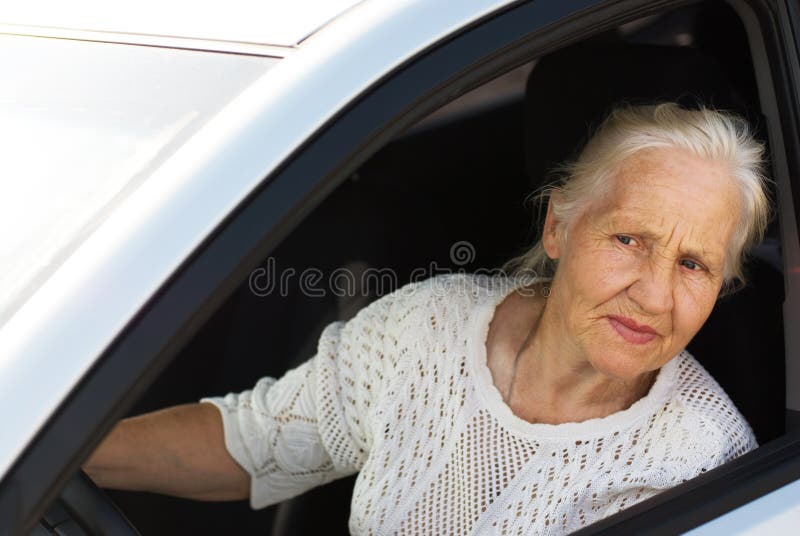 Attentive elderly woman driving car. Attentive elderly woman driving car