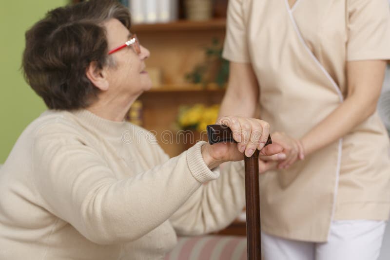 Elderly women trying to stand up with help of her caregiver. Elderly women trying to stand up with help of her caregiver
