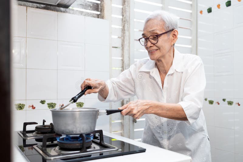 Bejaarden die groentesoep koken en de ingrediënten gezond voedsel verwarmen goede koken - bejaarde vrouw die staat