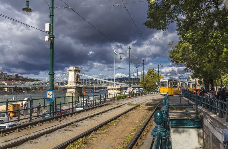 Bekende gele tramlijn 2 van Boedapest langs de Donau, voorbij een kettingbrug in royalty-vrije stock afbeeldingen Bekende gele tramlijn 2 van Boedapest langs de Donau, voorbij een kettingbrug in royalty-vrije stock afbeeldingen