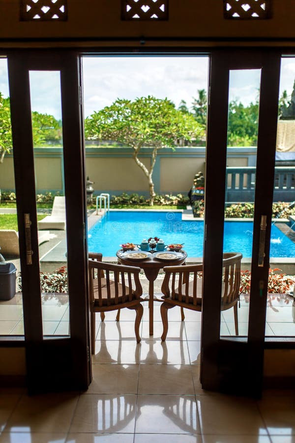 Bekijk vanuit de kamer, het Balinese tropische ontbijt van fruit, koffie en omelet voor twee mensen op de achtergrond van de pool stock fotografie Bekijk vanuit de kamer, het Balinese tropische ontbijt van fruit, koffie en omelet voor twee mensen op de achtergrond van de pool stock fotografie