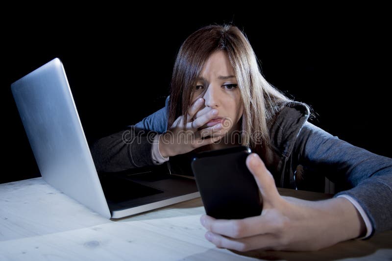 Bekymrad tonåring som använder mobiltelefonen och datoren, som internetcyberpennalismen förföljde det missbrukade offret royaltyfri foto Bekymrad tonåring som använder mobiltelefonen och datoren, som internetcyberpennalismen förföljde det missbrukade offret royaltyfri foto