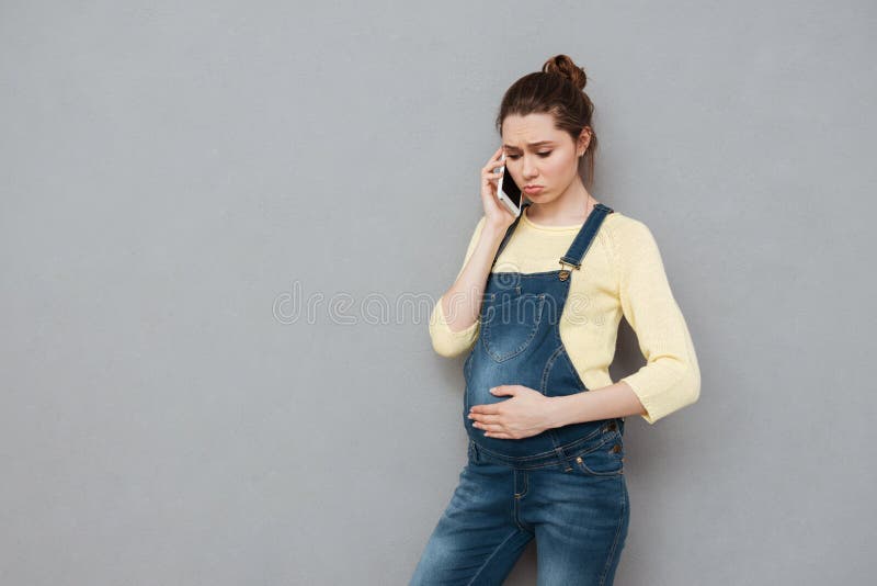 Bekymrad ung gravid kvinna som talar på mobiltelefonen arkivbilder Bekymrad ung gravid kvinna som talar på mobiltelefonen arkivbilder