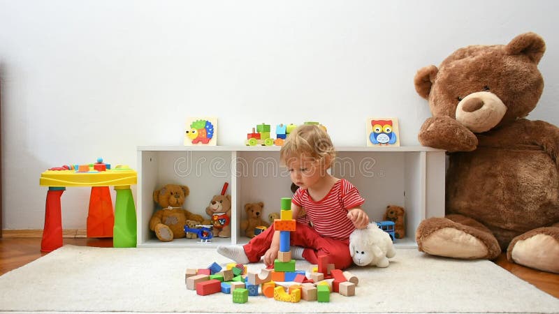 Bel bambino felice che si diverte a giocare con blocchi di legno colorati sul pavimento a casa. attività interna per bambini stock footage