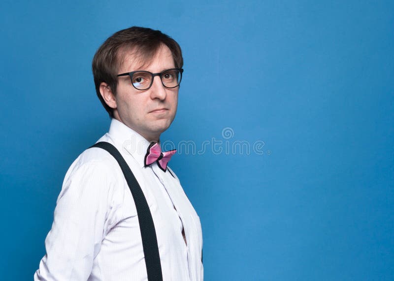 bel homme en chemise rose, noeud papillon, suspendant noir et lunettes regardant la caméra photographie stock bel homme en chemise rose, noeud papillon, suspendant noir et lunettes regardant la caméra photographie stock
