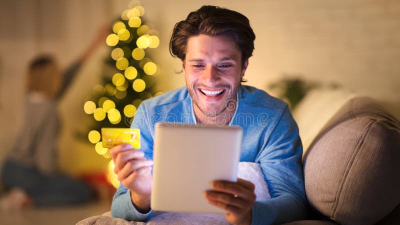 Bel homme magasiner en ligne sur tablette pour de nouvelles années eve photos libres de droits