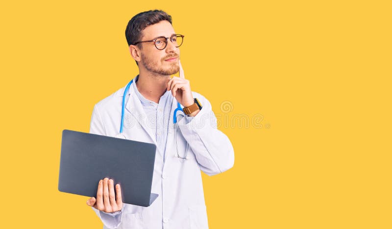 Handsome young man with bear wearing doctor uniform working using computer laptop serious face thinking about question with hand on chin, thoughtful about confusing idea. Handsome young man with bear wearing doctor uniform working using computer laptop serious face thinking about question with hand on chin, thoughtful about confusing idea