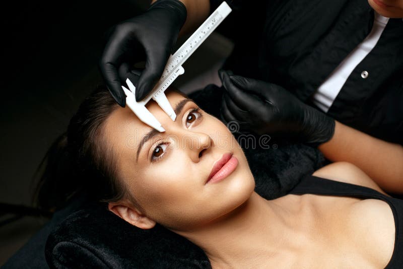 Mestre feminino colocar tinta sobrancelha no salão de beleza durante a  maquiagem