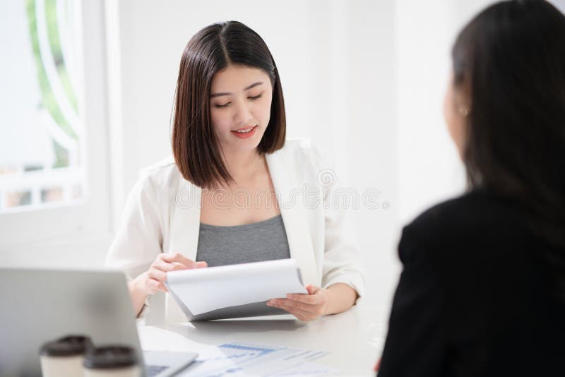 A bela mulher asiática lê o currículo e dá a entrevista como um recurso humano para o recrutamento de empresas com um