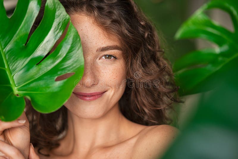 Bela mulher natural cobrindo seu rosto com folha tropical imagens de stock royalty free