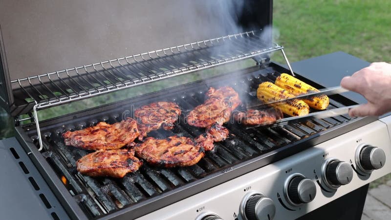 Bela vista do homem cozinhando bife de carne com milho na grelha a gás.