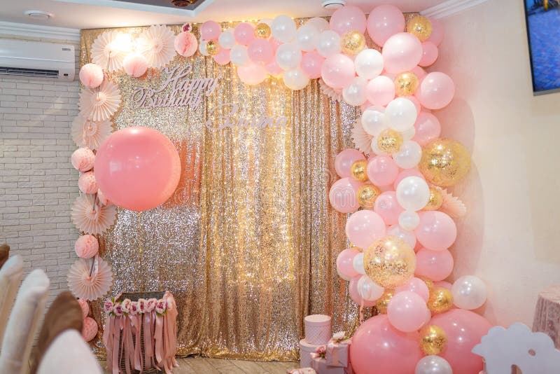 Beautiful pink decorations, wrapped present boxes with ribbons and bow, flowers and balloons on golden shiny background. Little girl birthday party decorations. Beautiful pink decorations, wrapped present boxes with ribbons and bow, flowers and balloons on golden shiny background. Little girl birthday party decorations