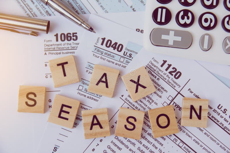 Belastingsseizoen met houten alfabetblokken, calculator, pen op de achtergrond van de 1040 belastingsvorm