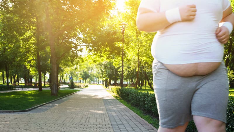 Obese man jogging in park, persistent in losing weight, big belly close up, stock photo. Obese man jogging in park, persistent in losing weight, big belly close up, stock photo