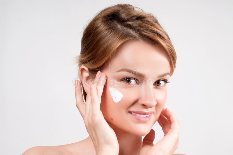 Beleza e conceito do skincare Jovem mulher que aplica o creme hidratante na cara imagem de stock royalty free Beleza e conceito do skincare Jovem mulher que aplica o creme hidratante na cara imagem de stock royalty free