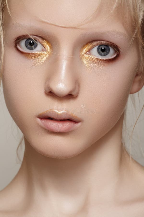 Beleza & forma. Face modelo com composição brilhante do ouro do feriado, pele limpa da menina imagem de stock Beleza & forma. Face modelo com composição brilhante do ouro do feriado, pele limpa da menina imagem de stock