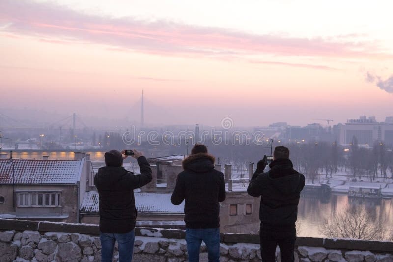 NnSilhouette of three people taking photos with their smartphones of the Belgrade landscape. NnSilhouette of three people taking photos with their smartphones of the Belgrade landscape