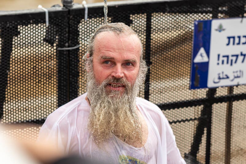 Believers som anländer till Epiphany Rite använder heligt vatten för att borsta sig från Jordanfloden på Jesus Kristus baptismala royaltyfria bilder