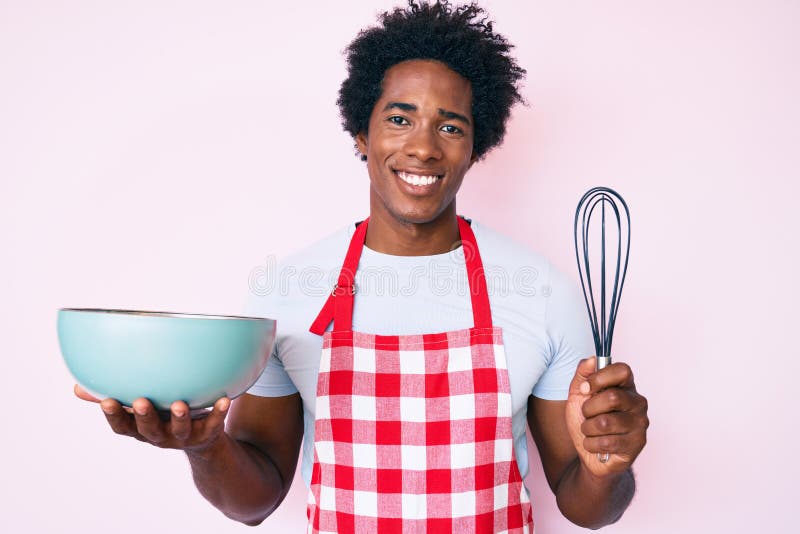 Bell'afro-americano con una cucina afro-peli usando baker whisky con un sorriso allegro e fresco sulla faccia