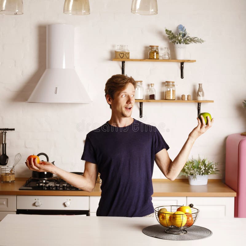 Bell'uomo attivo e sano si sente felice quando mangia la mela. giovani e attraenti che mangiano alimenti sani in cucina a casa. be fotografie stock