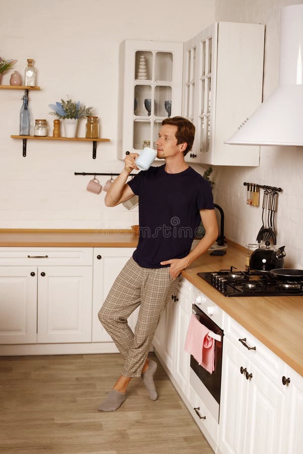 Bell'uomo che beve caffè o tè a casa in cucina. concetto di routine mattutina fotografia stock libera da diritti