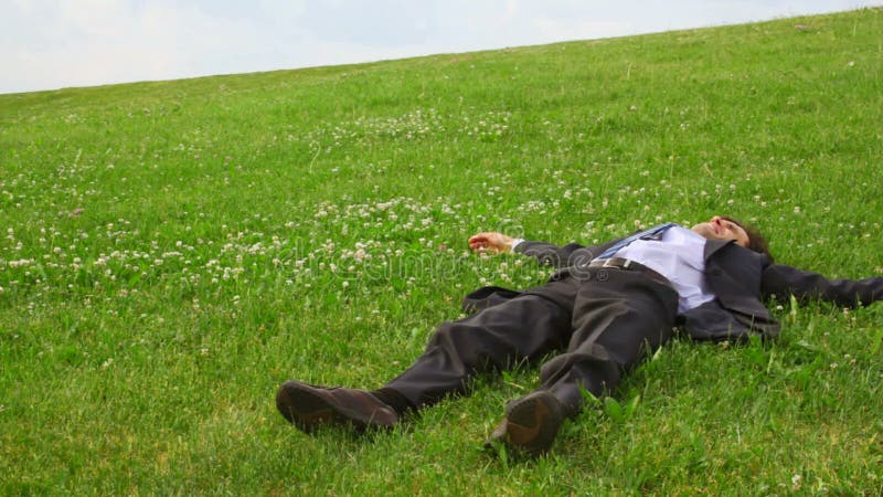 Bell'uomo in completo sdraiato sull'erba verde e video d archivio