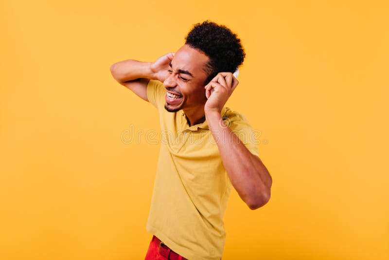 Bell'uomo felice che si diverte a suonare. foto in interni di un modello di nero alla moda sulle cuffie ballando o immagini stock libere da diritti