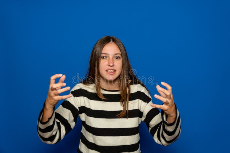 Bella adolescente ispanica di circa 15 anni con un maglione a strisce con le mani applaudite in segno di rabbia e fotografia stock