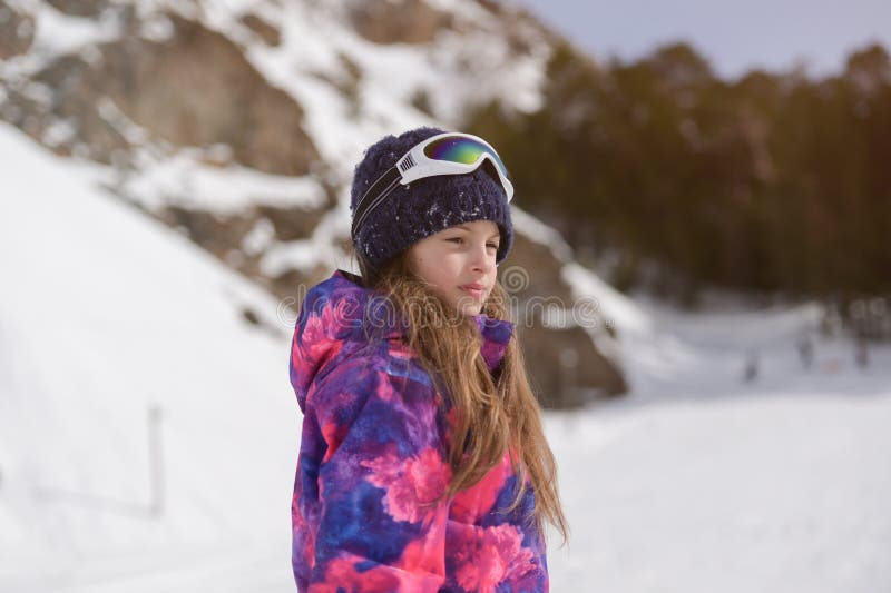 Bella Adorable Niña Americana Activa Con Traje De Esquí Sombrero De Lana Y Gafas En El Fondo De Un Resort Montaña De Nieve Al a Foto de - Imagen de