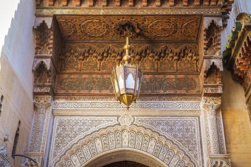 Bella arte marocchina nella città di Fes Soffitto scolpito di legno, lampada antica ed arte di arabesque sulla parete morocco immagine stock Bella arte marocchina nella città di Fes Soffitto scolpito di legno, lampada antica ed arte di arabesque sulla parete morocco immagine stock
