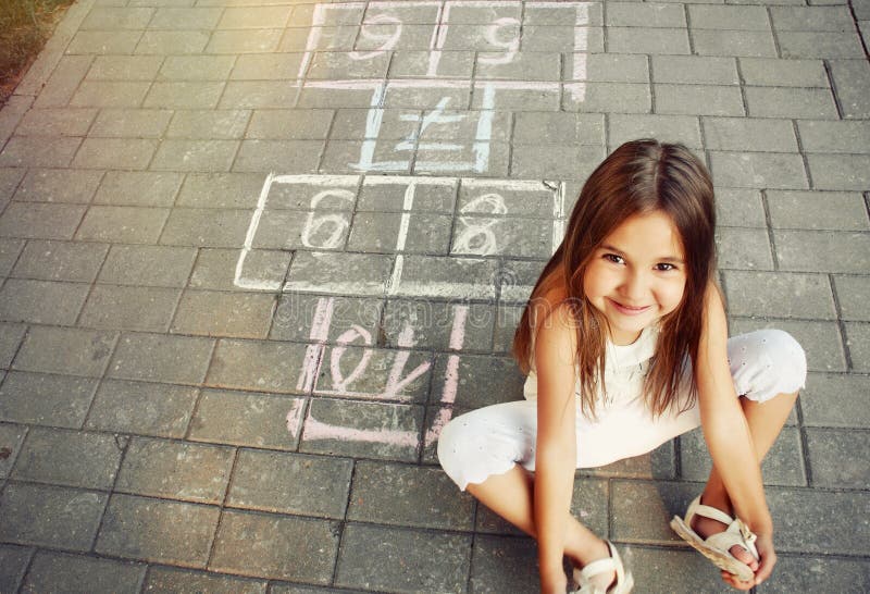 Bella bambina allegra che gioca a campana sul campo da giuoco immagine stock Bella bambina allegra che gioca a campana sul campo da giuoco immagine stock