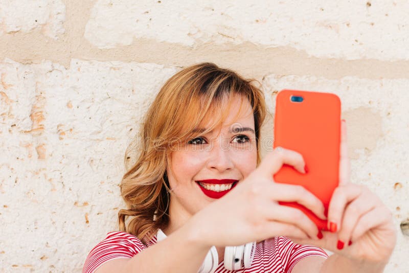 Bella bionda che fa un selfie per strada col cellulare immagine stock