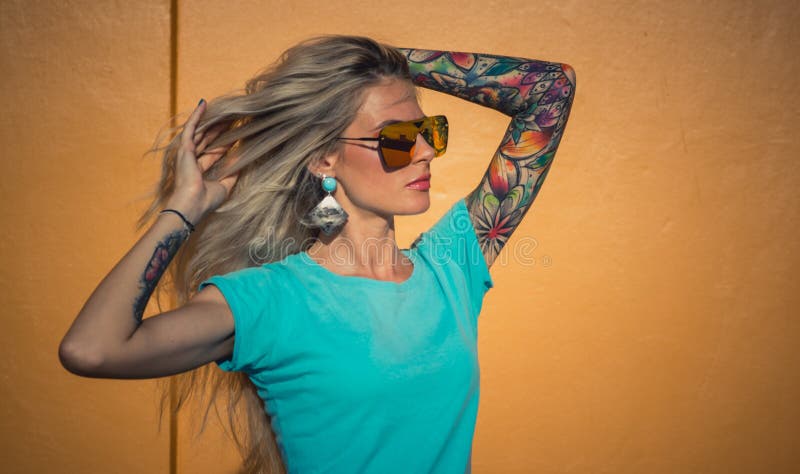 Bella bionda in occhiali da sole che posano alla macchina fotografica Ritratto sui precedenti della parete arancio luminosa Panta fotografie stock libere da diritti Bella bionda in occhiali da sole che posano alla macchina fotografica Ritratto sui precedenti della parete arancio luminosa Panta fotografie stock libere da diritti