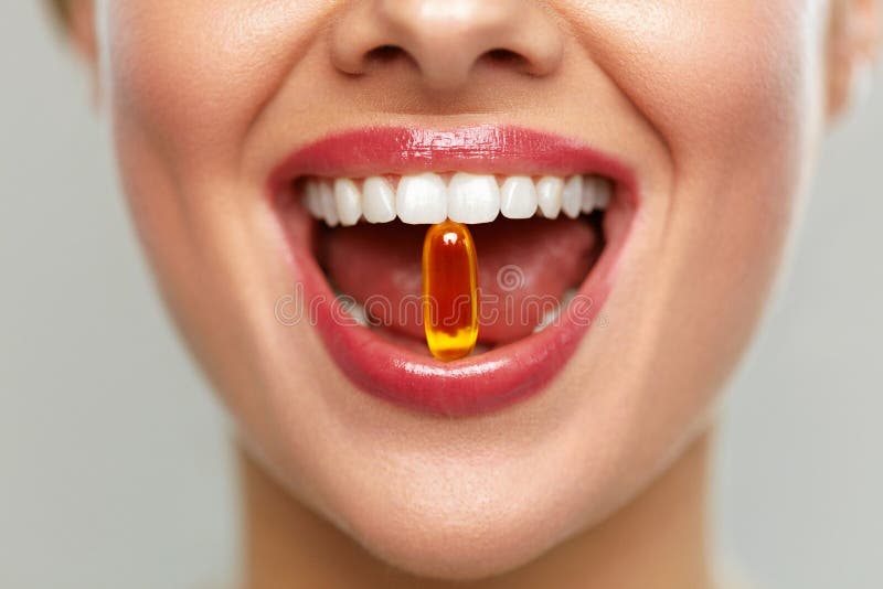 Bella bocca della donna con la pillola in denti Ragazza che prende le vitamine
