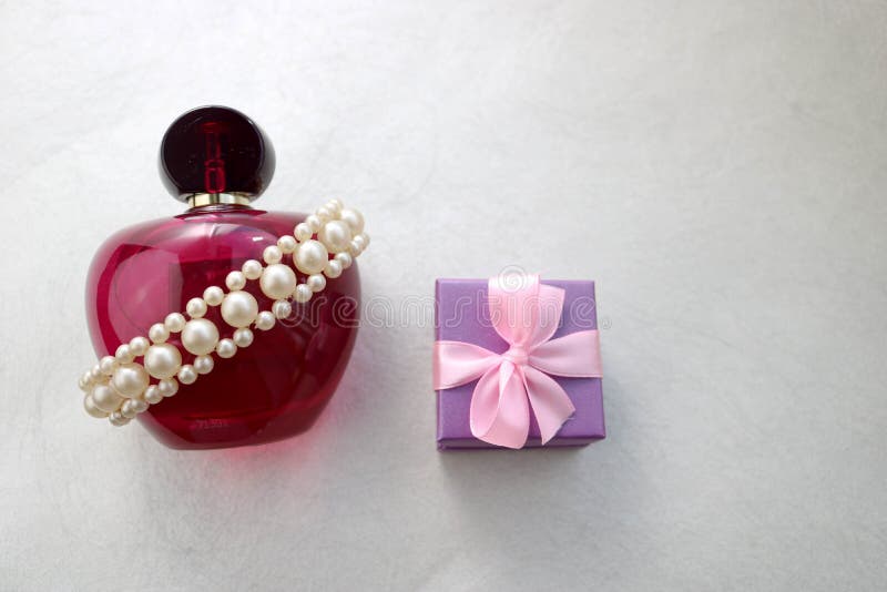 Bella bottiglia trasparente di vetro rosa di profumo femminile decorata con le perle preziose bianche e piccoli contenitore di re immagini stock Bella bottiglia trasparente di vetro rosa di profumo femminile decorata con le perle preziose bianche e piccoli contenitore di re immagini stock