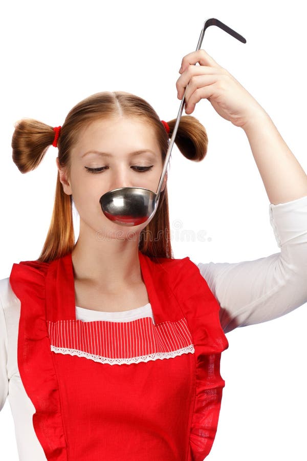 Young beautiful attractive housewife in bright red apron with funny ponytails tasting meal from ladle isolated on white background. Close up. Young beautiful attractive housewife in bright red apron with funny ponytails tasting meal from ladle isolated on white background. Close up.