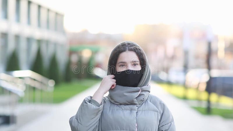 Bella chica quita la máscara protectora en la calle de la ciudad. la mujer utiliza un dispositivo de protección coronavirus en el almacen de video