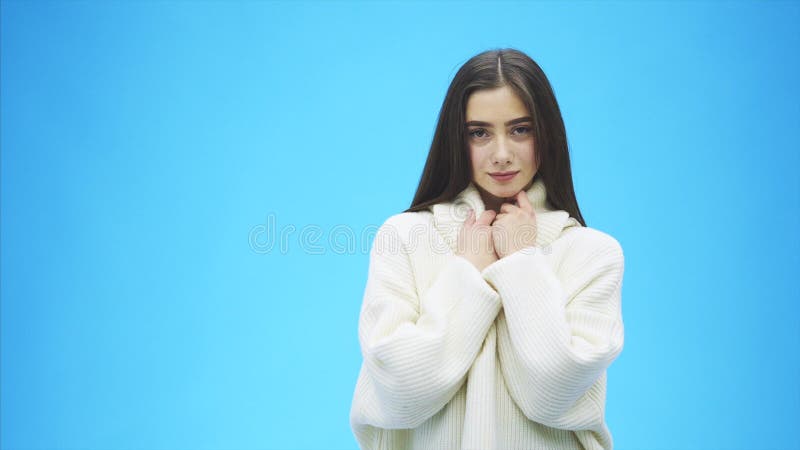 Bella condizione della ragazza su un fondo blu Durante questo tempo è vestita in un maglione bianco Con il nero lungo