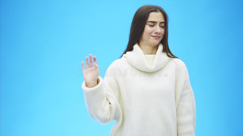 Bella condizione della ragazza su un fondo blu Durante questo tempo è vestita in un maglione bianco Con il nero lungo