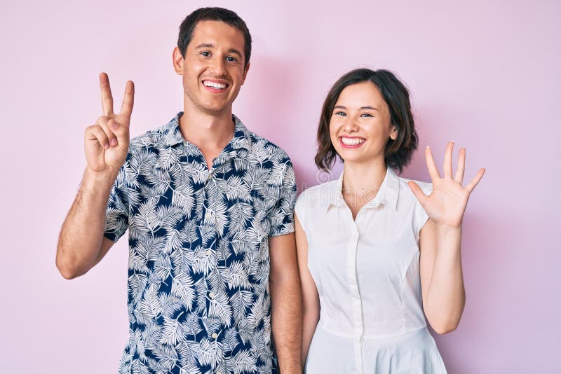 Bella coppia che indossa vestiti casuali che si esibiscono e puntano con le dita numero sette mentre sorride sicura e felice immagine stock