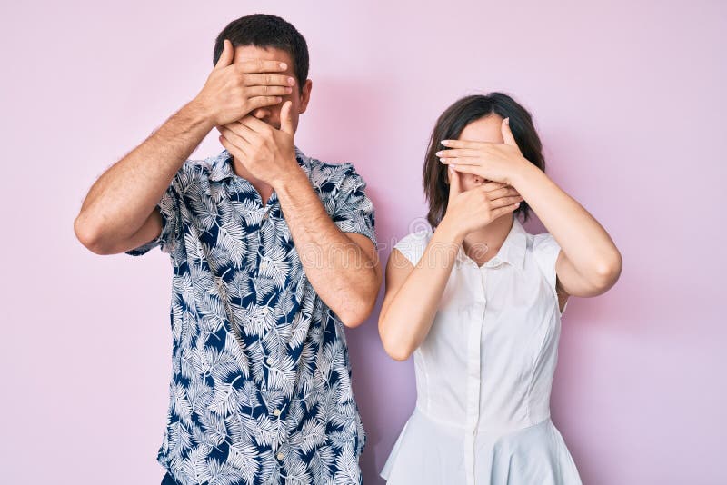 Bella coppia con abiti casuali che ricoprono occhi e bocca con mani sorprese e scioccate immagini stock libere da diritti