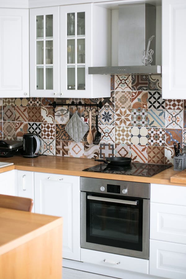Bella cucina reale bianca alla moda nello stile scandinavo con la cima di legno e le mattonelle spagnole immagini stock libere da diritti Bella cucina reale bianca alla moda nello stile scandinavo con la cima di legno e le mattonelle spagnole immagini stock libere da diritti