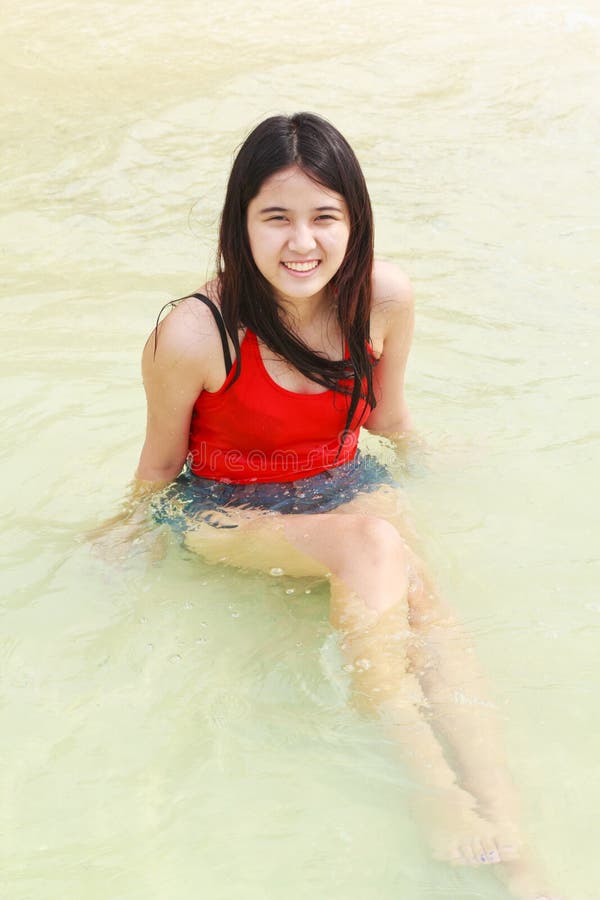 Bella donna asiatica che si siede sulla spiaggia immagini stock Bella donna asiatica che si siede sulla spiaggia immagini stock