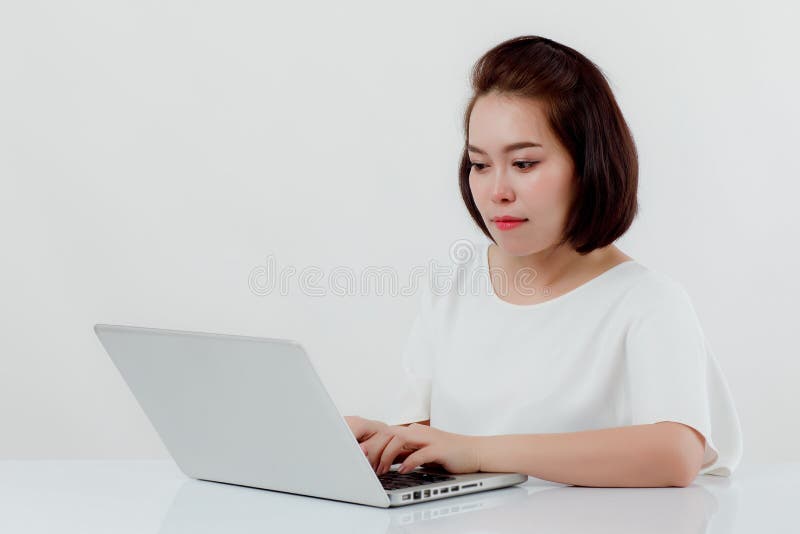 Bella donna asiatica che si siede in una camicia bianca sulla reception, c'è un computer portatile disposto L'espressione là è la fotografia stock Bella donna asiatica che si siede in una camicia bianca sulla reception, c'è un computer portatile disposto L'espressione là è la fotografia stock