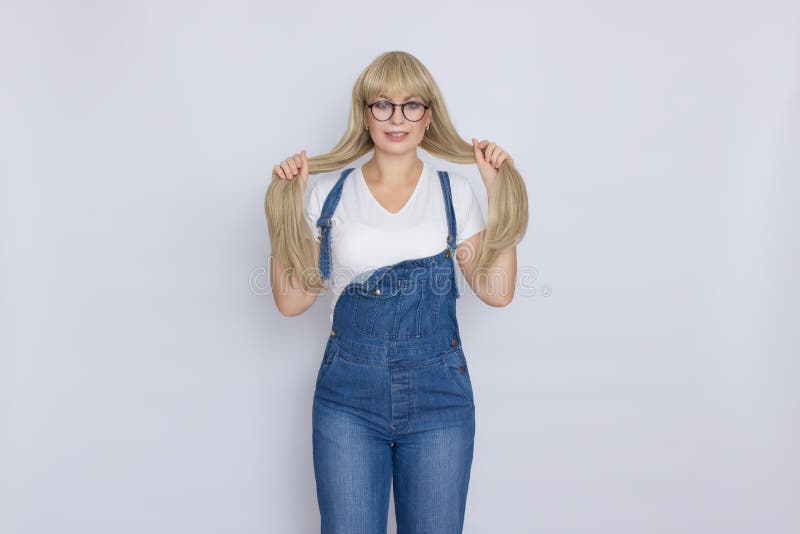 Bella donna bionda dolce con capelli lunghi in camici e vetri delle blue jeans sopra fondo grigio fotografia stock libera da diritti Bella donna bionda dolce con capelli lunghi in camici e vetri delle blue jeans sopra fondo grigio fotografia stock libera da diritti