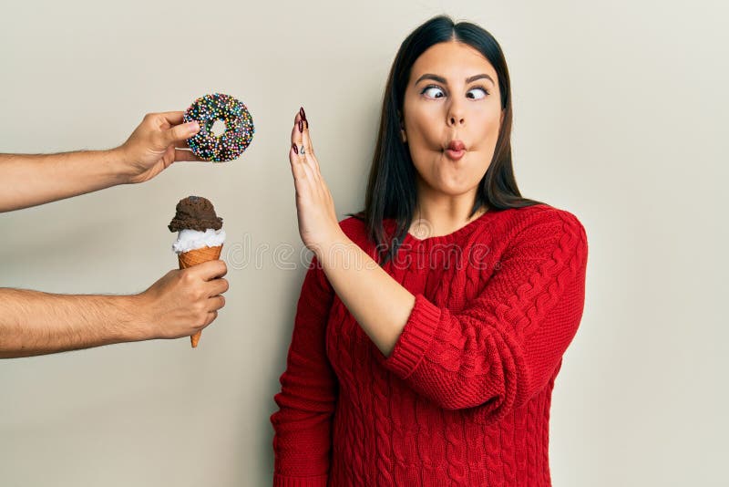 Beautiful brunette woman saying no to sweets on a healthy diet making fish face with mouth and squinting eyes, crazy and comical. Beautiful brunette woman saying no to sweets on a healthy diet making fish face with mouth and squinting eyes, crazy and comical