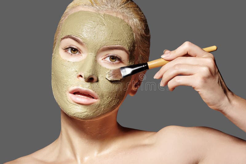 Bella donna che applica maschera facciale verde. Trattamenti di bellezza. La ragazza termale applica la maschera facciale di argil
