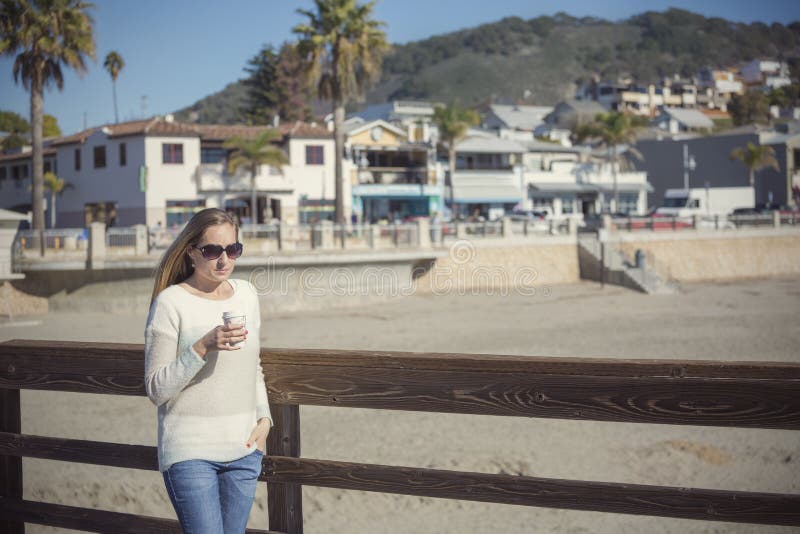 Bella donna che beve il suo caffè di mattina che cammina lungo il sentiero costiero fotografia stock libera da diritti Bella donna che beve il suo caffè di mattina che cammina lungo il sentiero costiero fotografia stock libera da diritti